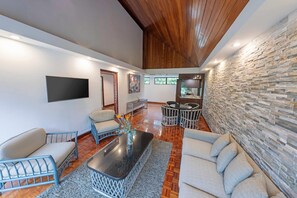 Un amplio salón con pared de piedra, un televisor de pantalla plana y un comedor.