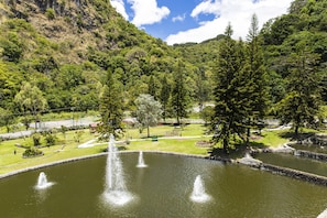 A serene park with a pond, fountains, and lush greenery.