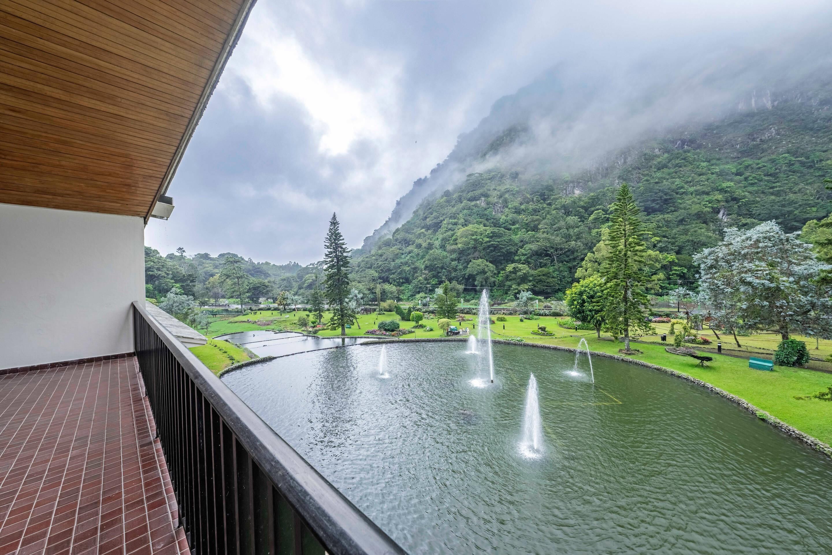 Un balcón con vista a un estanque y un jardín exuberante.