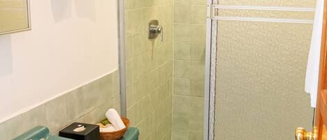 A bathroom with a green sink, a toilet, and a glass-enclosed shower.