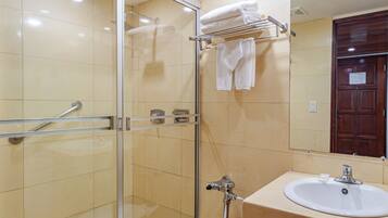Un baño moderno con cabina de ducha de vidrio, inodoro blanco y lavamanos con espejo superior.