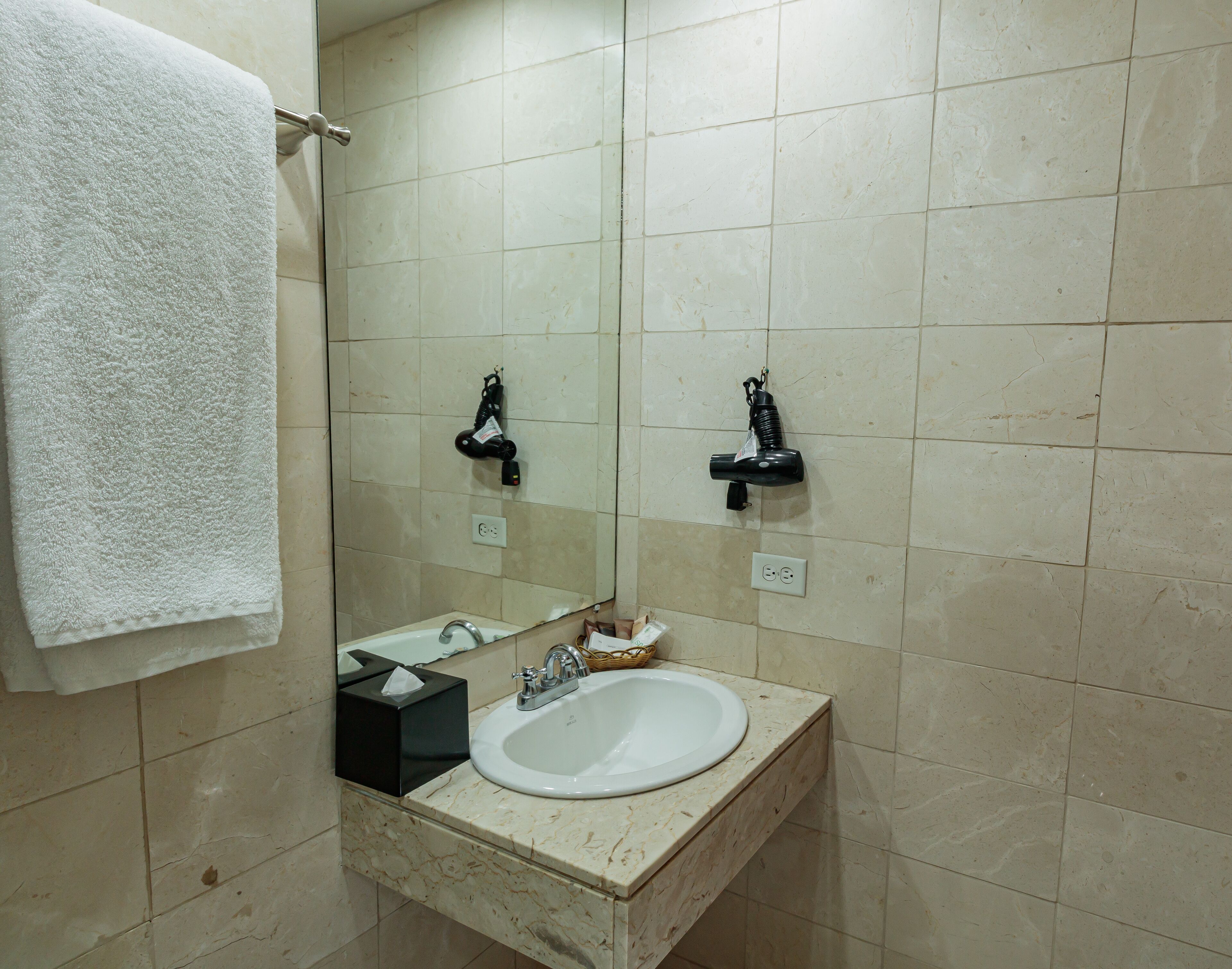 A bathroom with a white sink, a mirror, and a towel hanging on a rack.