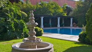 A garden with a fountain, a pool, and a covered area with columns. - Hotel Gobernador (Durango)