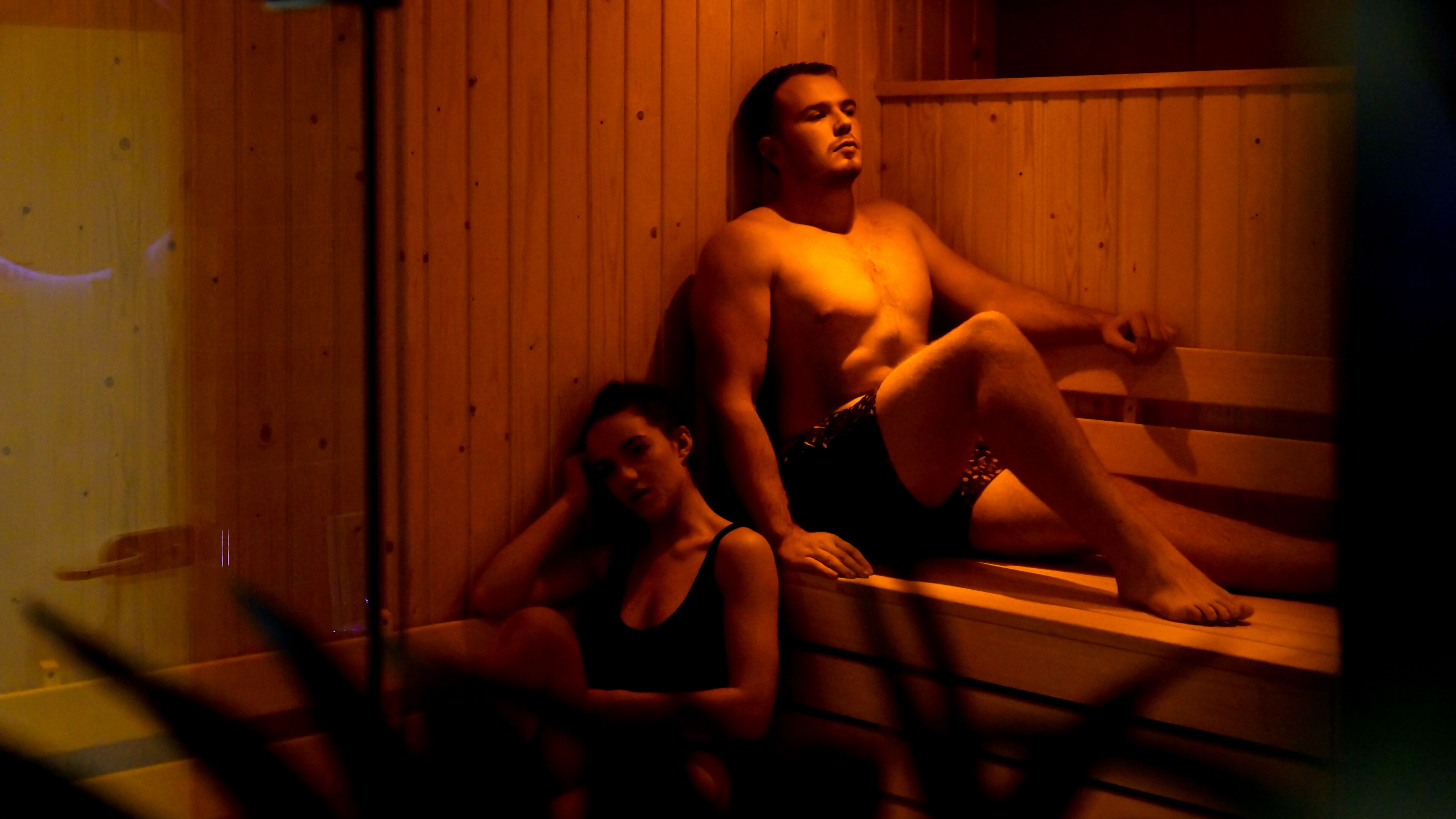 A sauna with wooden benches and a person sitting on one of them.