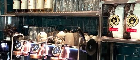 A coffee machine with multiple brewing stations, a selection of coffee beans, and a variety of glasses on display.