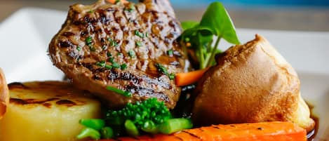A plate with grilled meat, roasted potatoes, grilled carrots, and a small round vegetable, possibly a potato or sweet potato.