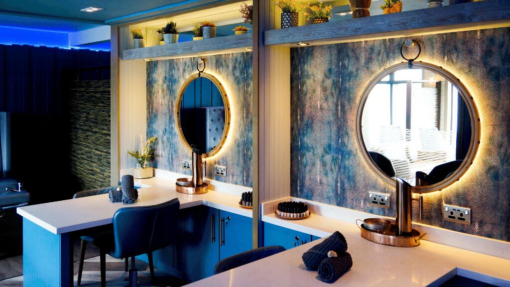 Une salle de bain moderne avec un grand miroir, un lavabo et des toilettes. On trouve des objets décoratifs sur le comptoir et sur les étagères au-dessus du miroir.