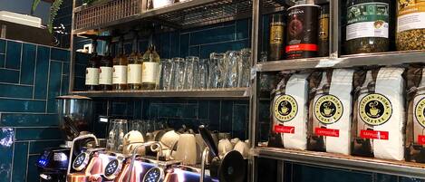 Ein Café-Interieur mit Espressomaschinen, Kaffeebohnen und Gläsern auf Regalen.