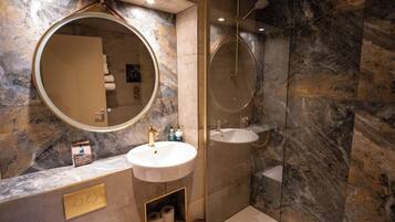 A modern bathroom with a round mirror, a sink, and a shower.