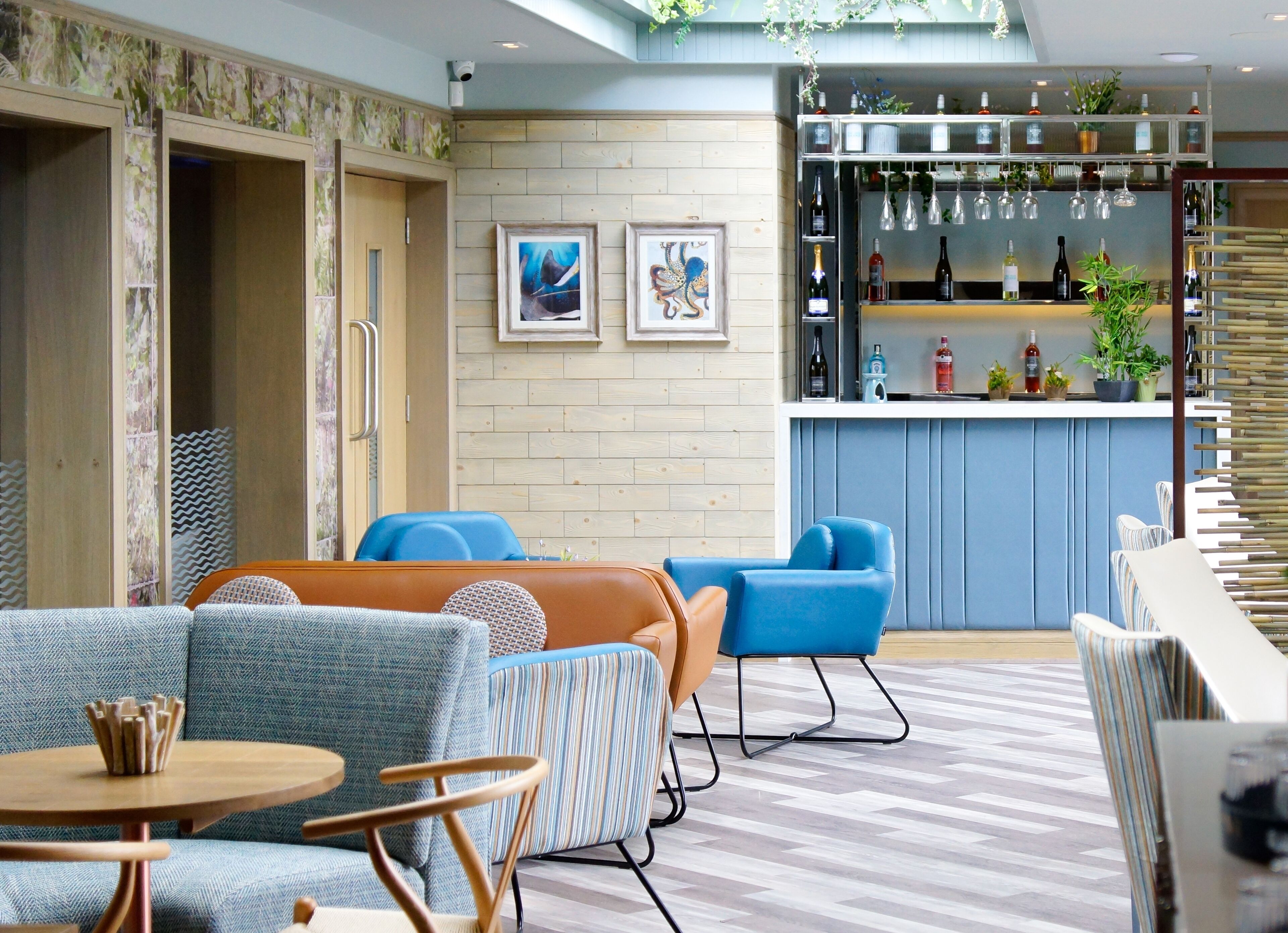 A modern lounge area with sofas, a bar, and framed artwork on the wall.