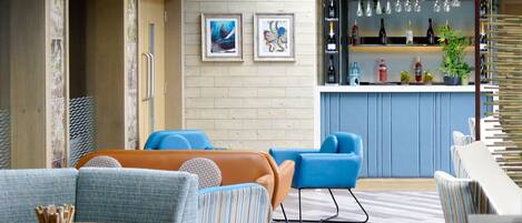 A modern lounge area with sofas, a bar, and framed artwork on the wall.