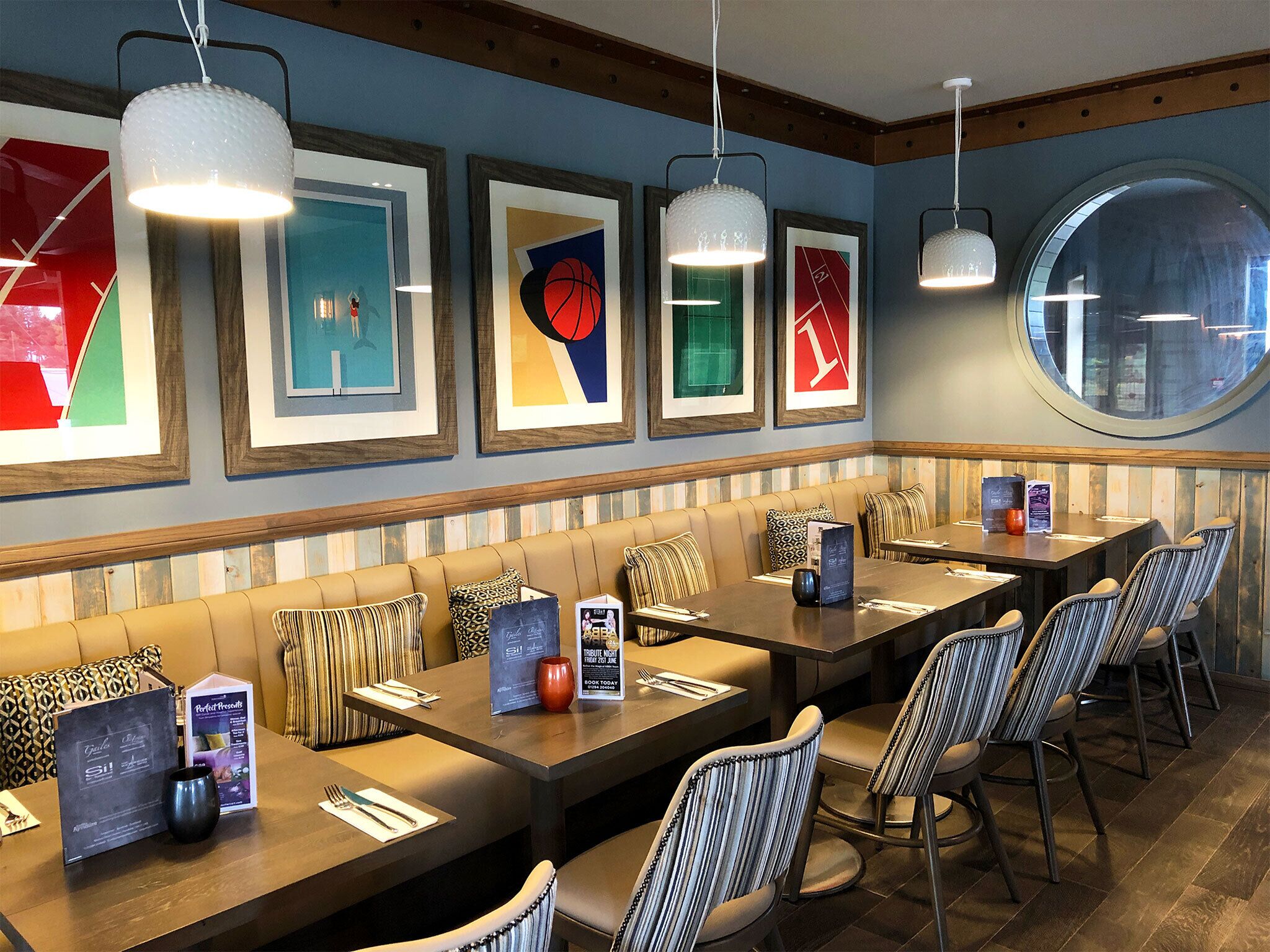A restaurant with a long counter, cushioned seating, and framed artwork on the wall.