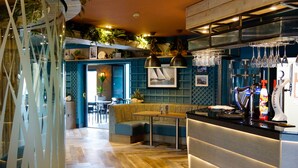 A bar area with a counter, stools, and a seating area with a bench. - The Gailes Hotel and Spa (Irvine)