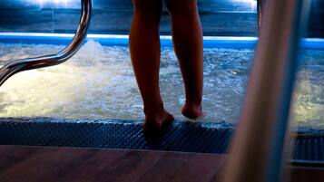 Una persona de pie al borde de un jacuzzi con barandilla de metal.