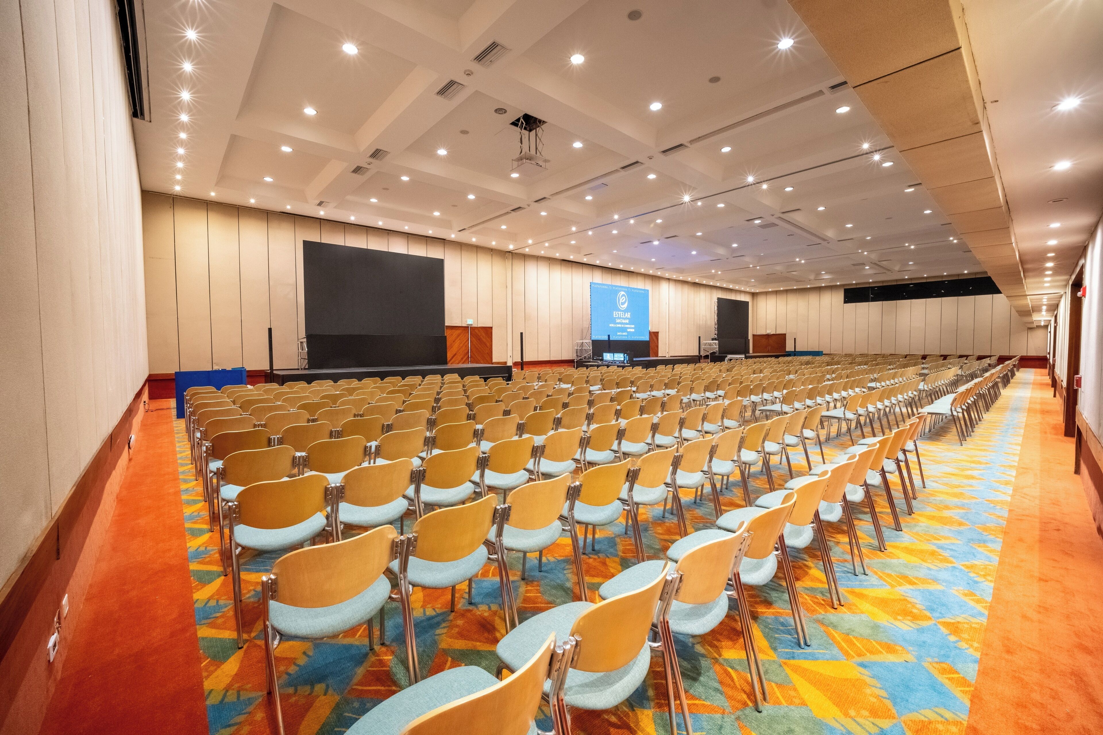 A conference room with rows of chairs, a large screen, and a podium.