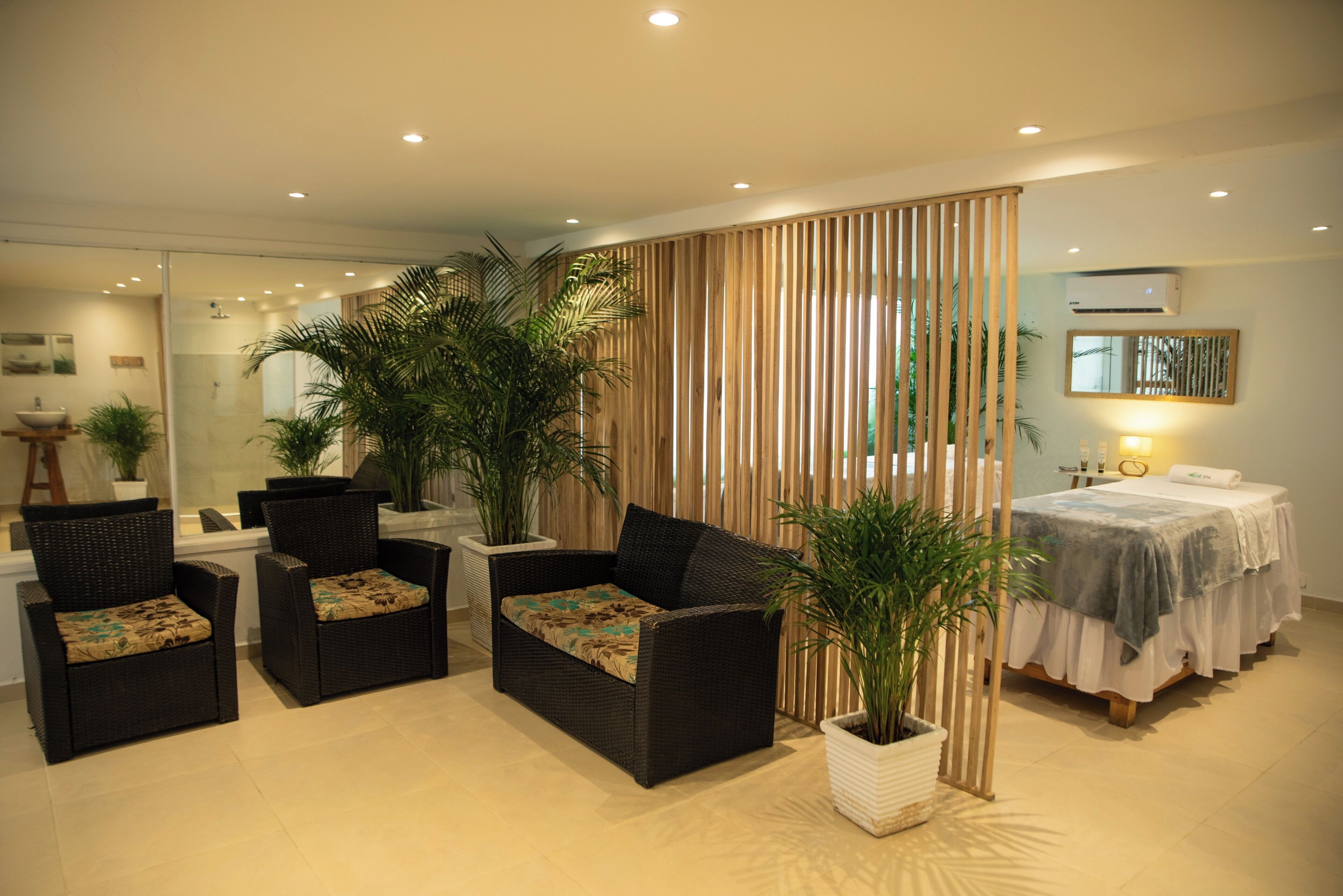 Une pièce moderne comprenant un canapé, des fauteuils, un lit et des plantes en pot.