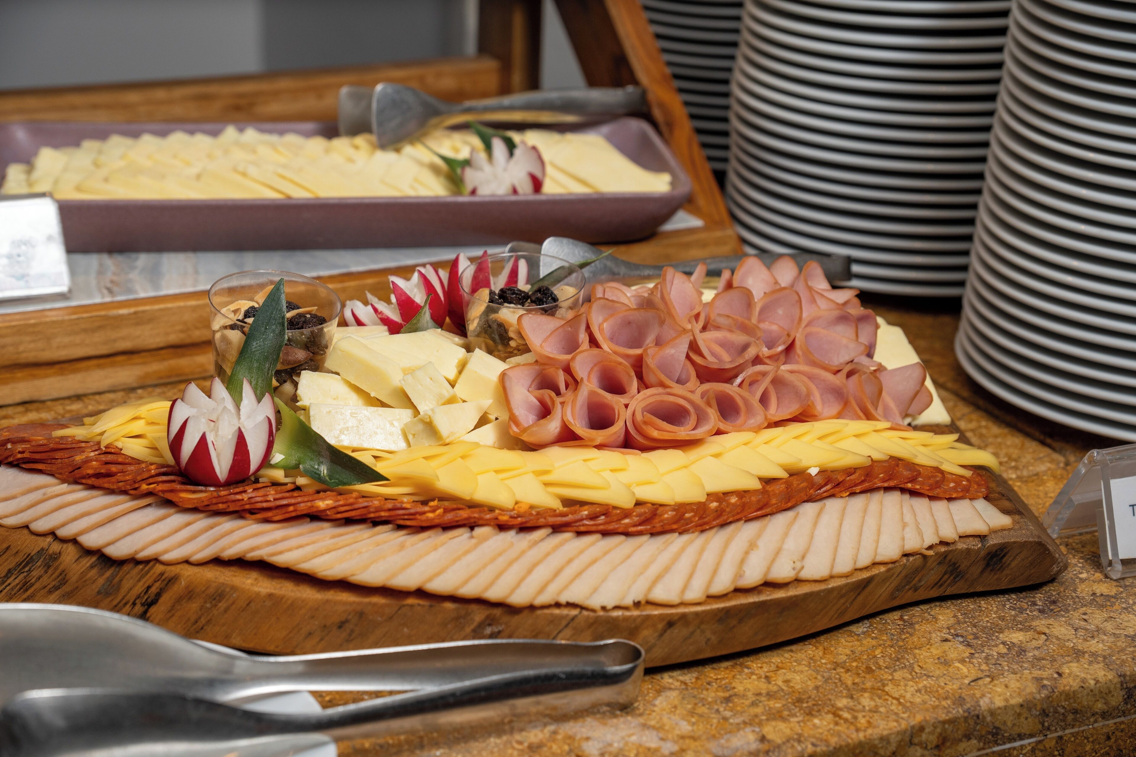Un buffet proposant une variété de fromages, de viandes et de garnitures, le tout présenté sur une planche en bois.