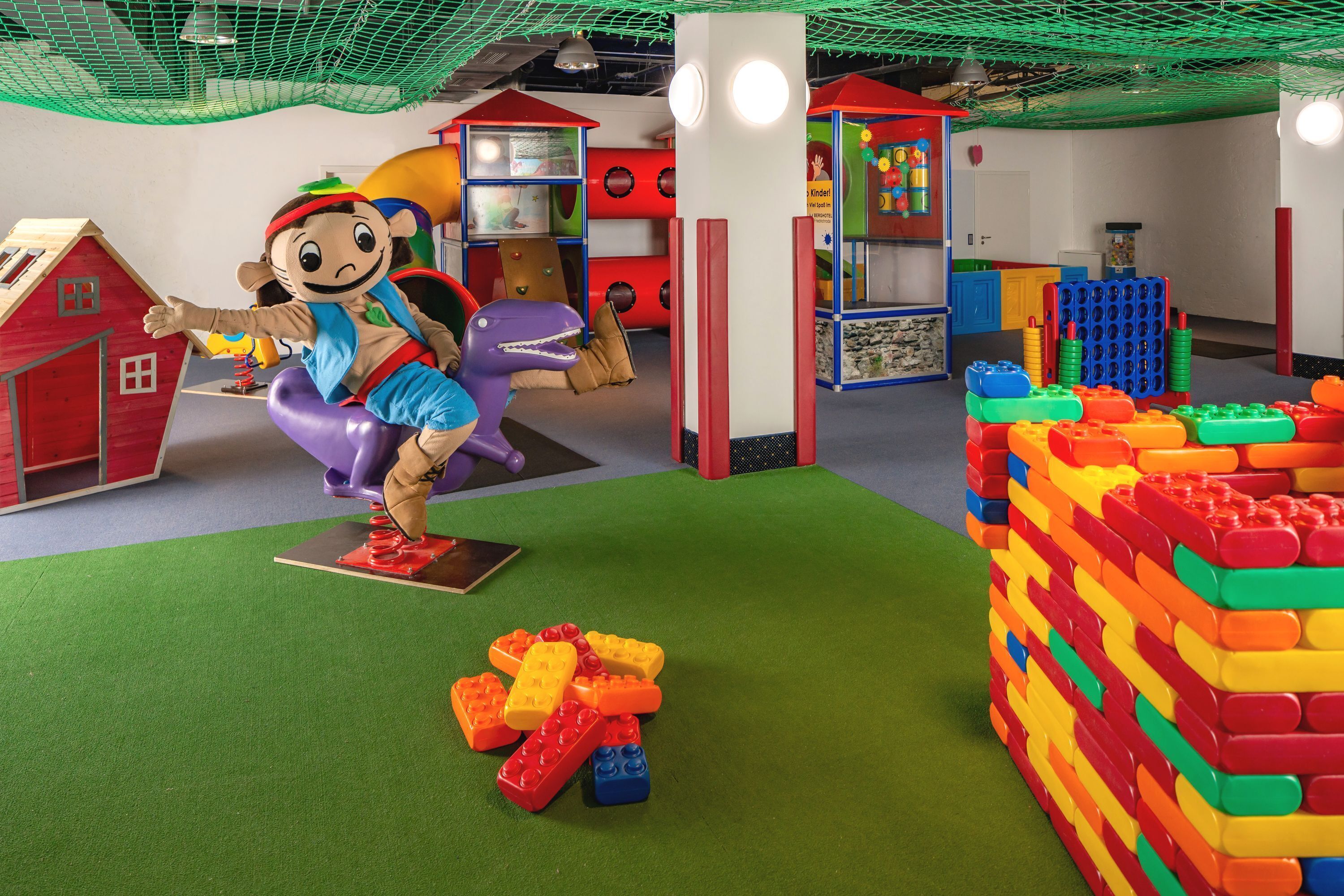 A children's play area with a mascot, play structures, and building blocks.