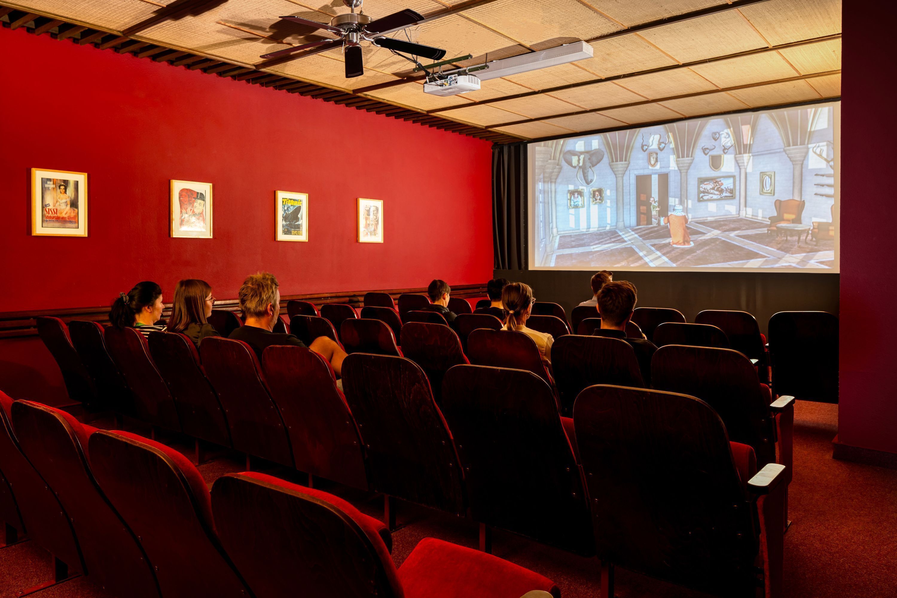 Ein Auditorium mit Reihen von Sitzen, die auf einen großen Bildschirm zeigen, auf dem ein Bild projiziert wird.