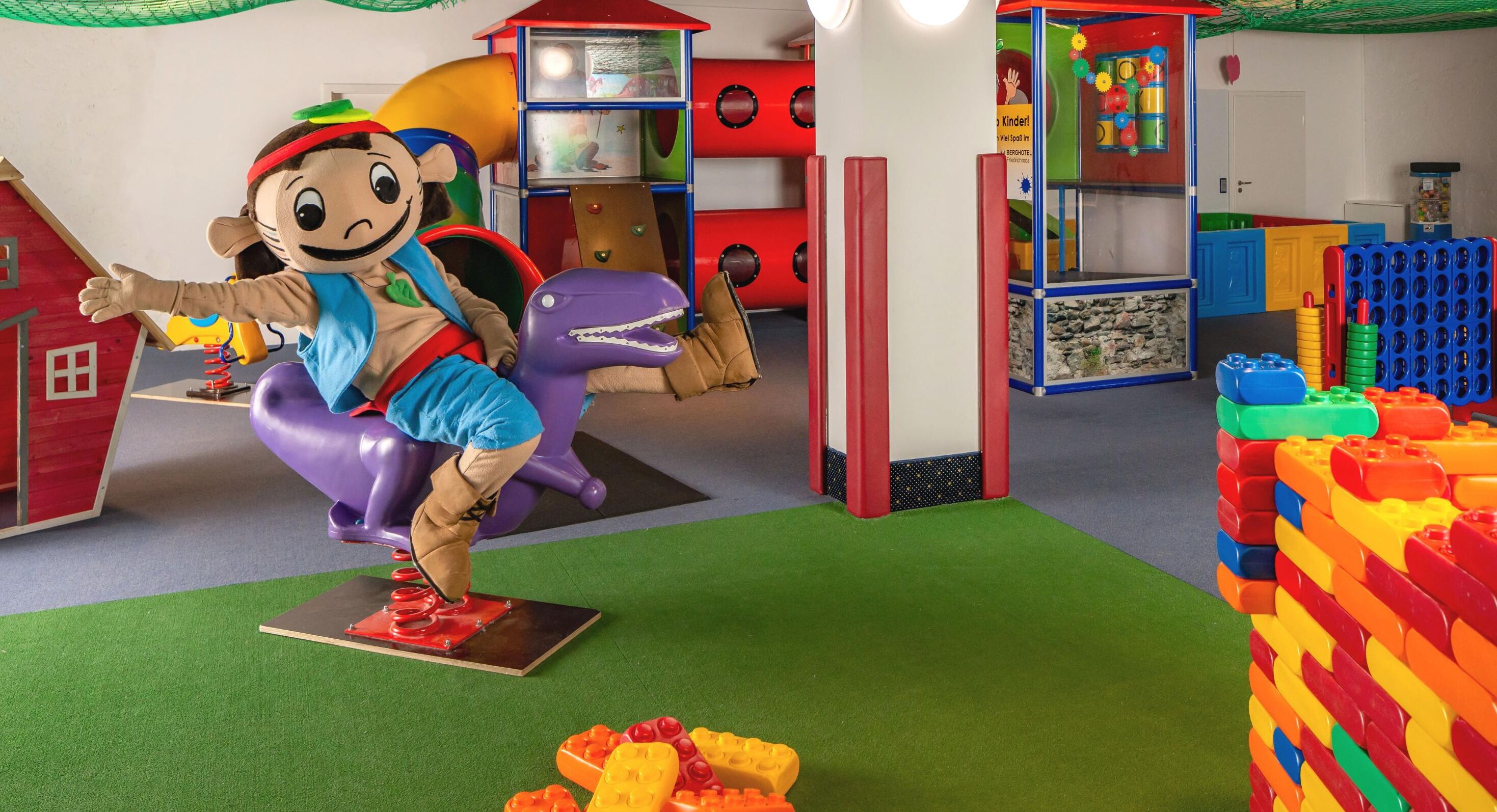 A play area with a large dinosaur figure, colorful play structures, and a variety of toys.
