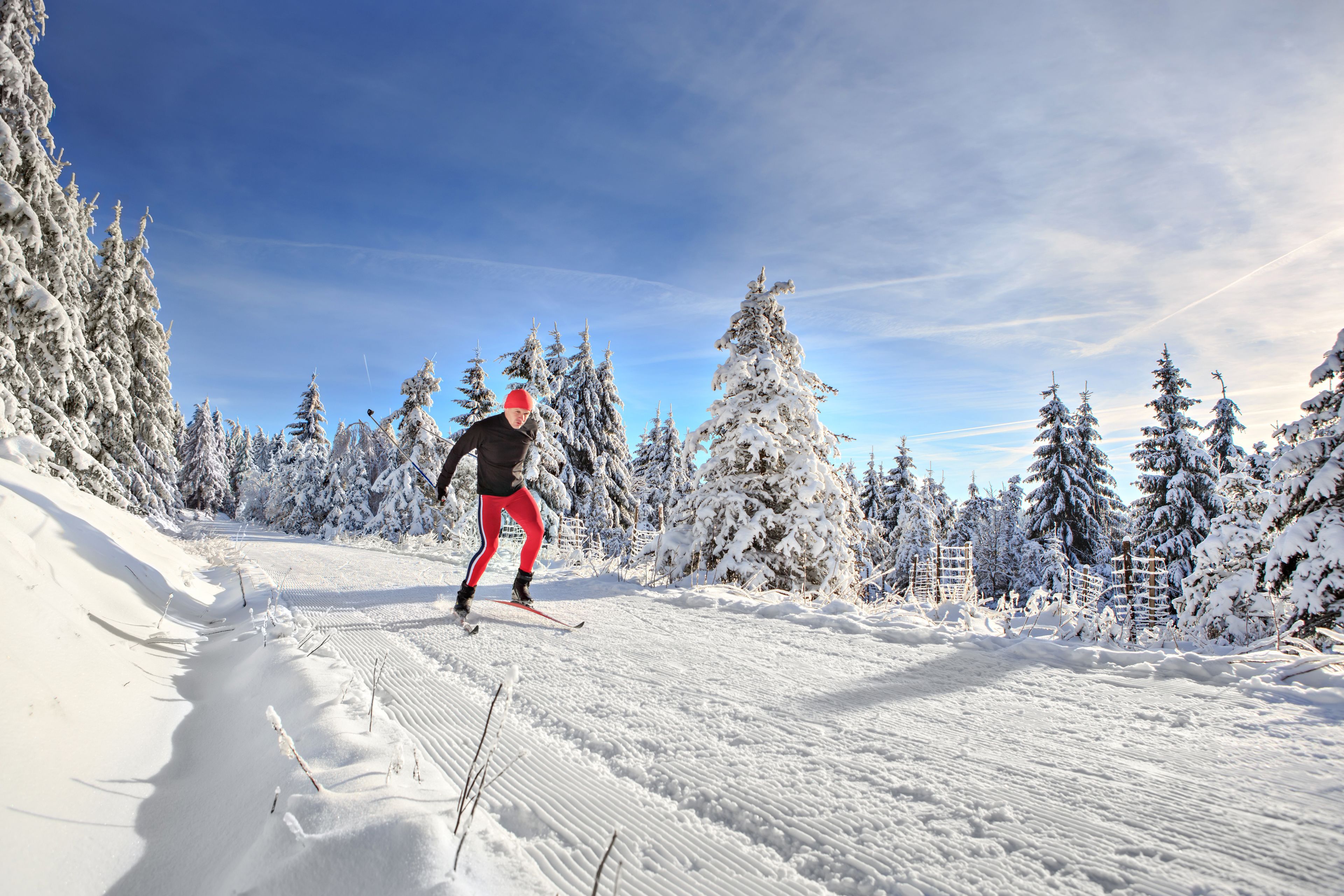 Schneebedeckte Landschaft mit einer Person beim Skifahren.