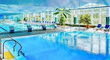 Una piscina techada, una piscina al aire libre de temporada, sombrillas