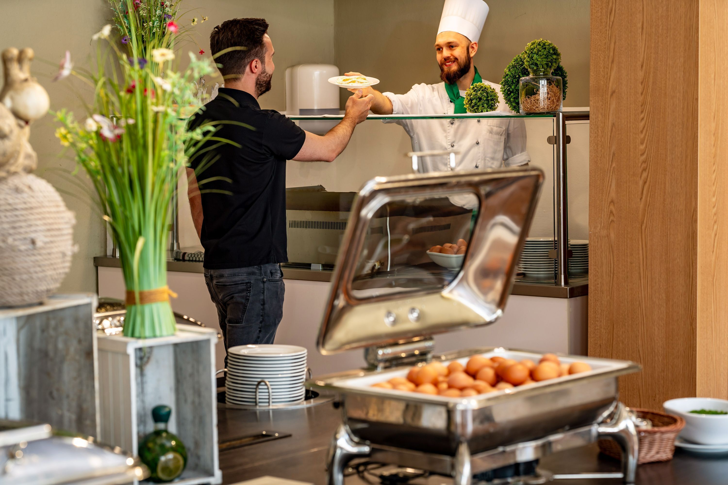 Un buffet proposant une variété de plats, notamment un présentoir avec un couvercle en verre et un saladier rempli d’œufs.