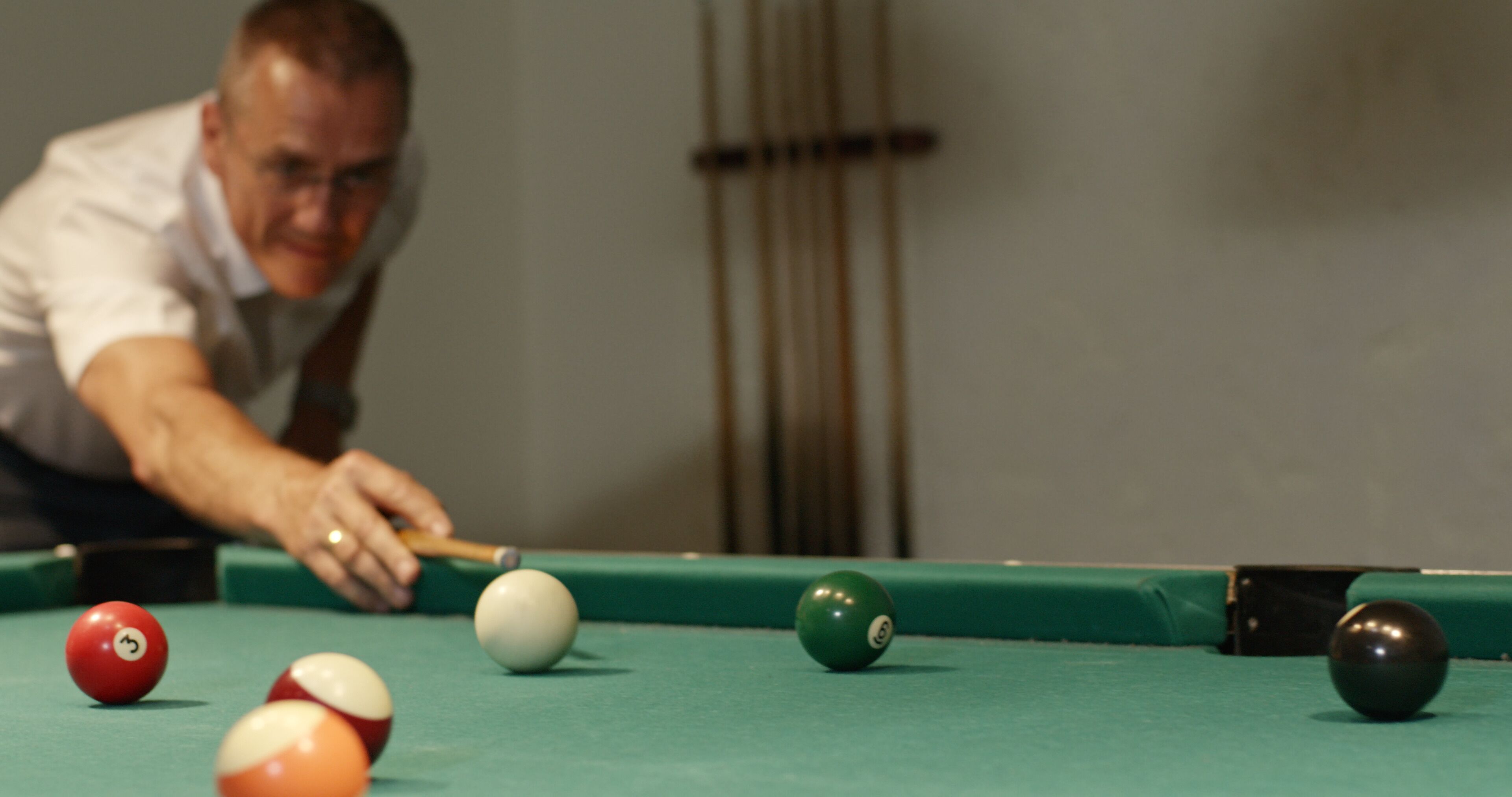A pool table with balls and a cue stick.