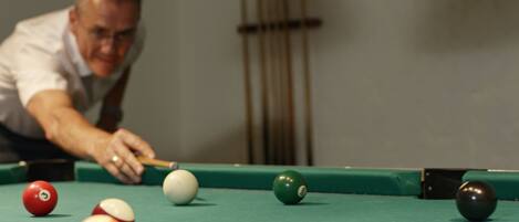 A pool table with balls and a cue stick.
