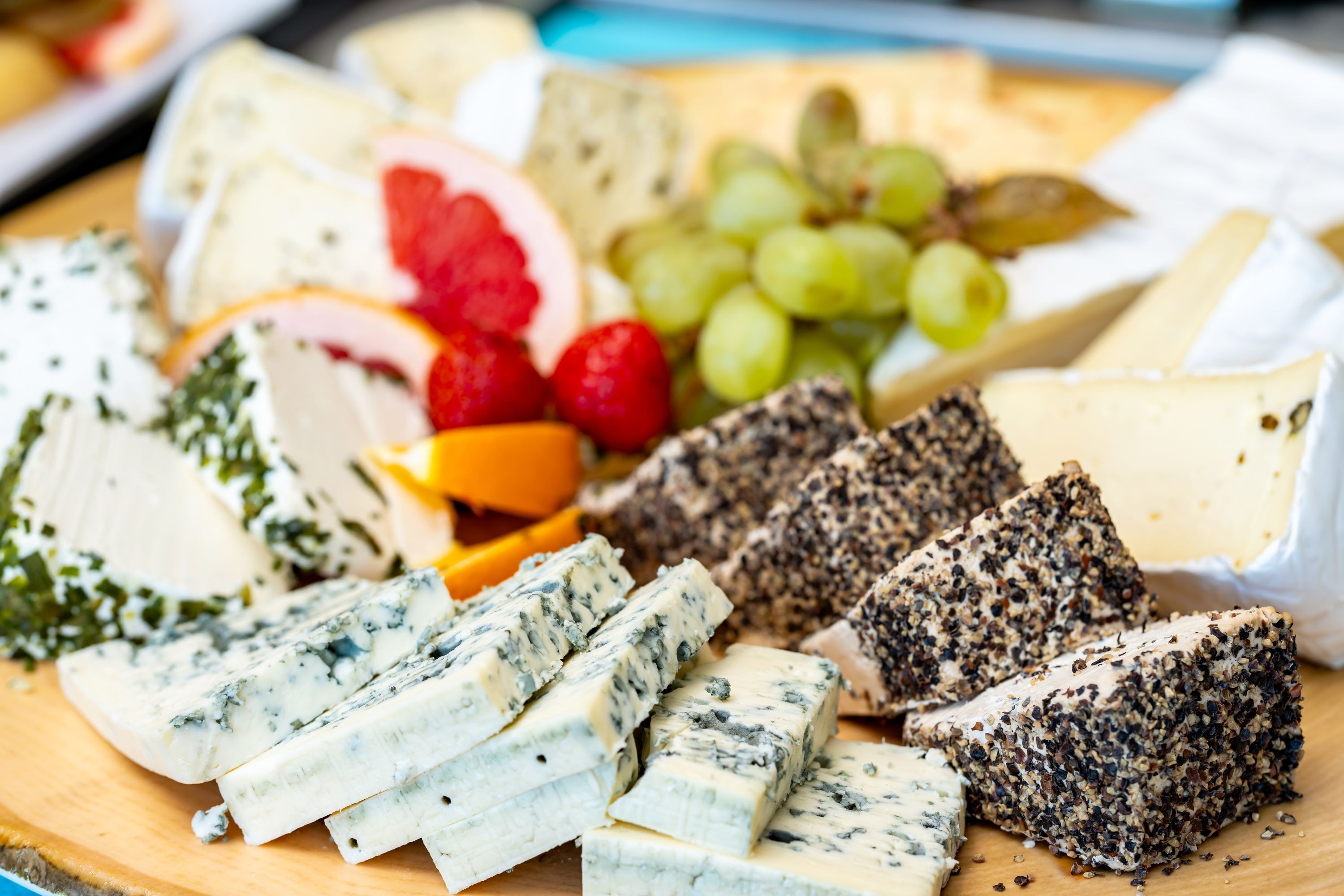 A variety of cheeses and fruits on a wooden board.