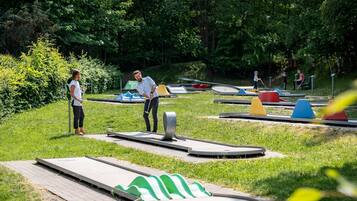 Un parc avec une piste de bowling, de l’herbe verte et des arbres.