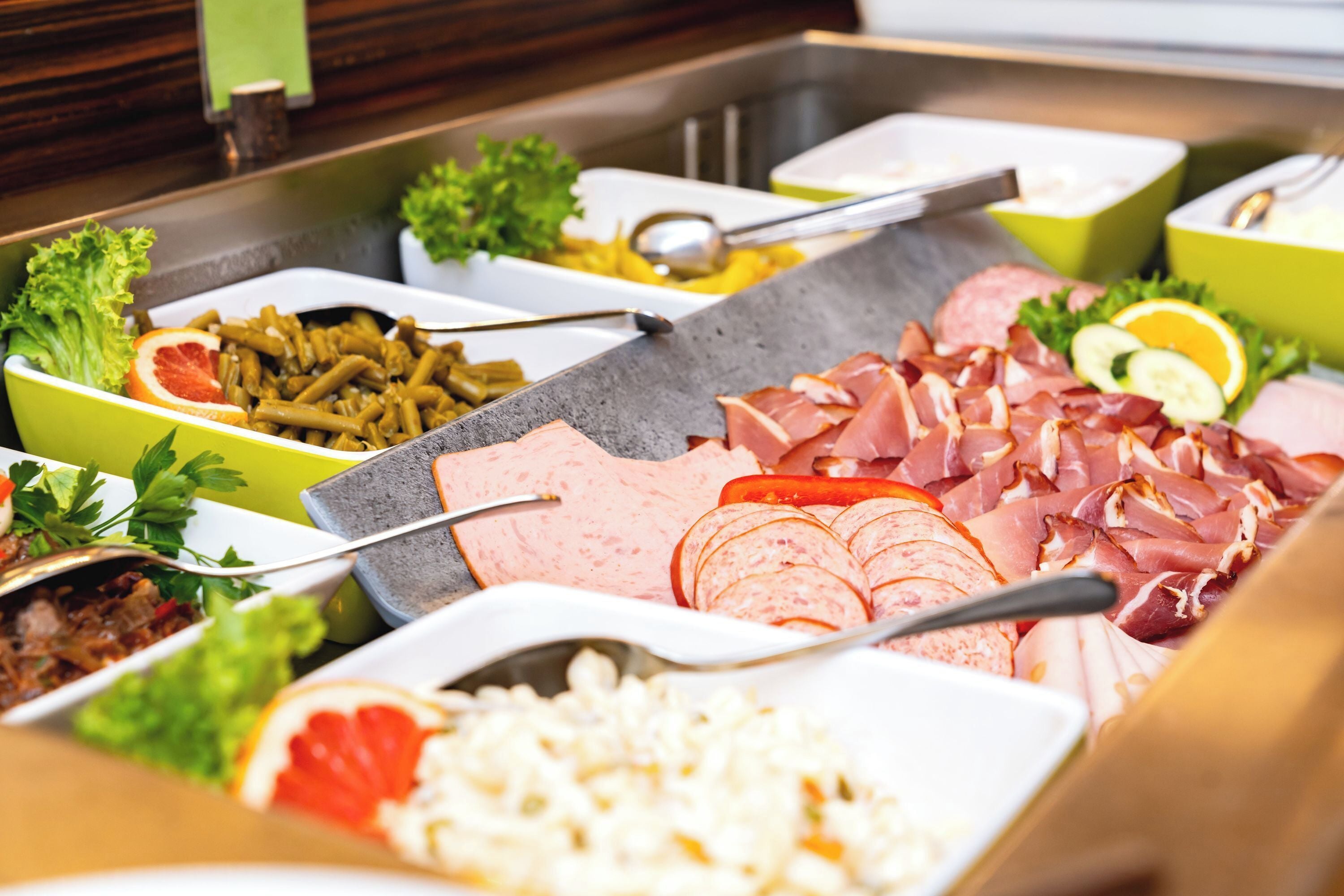 Un bufé con diversas opciones de comida, incluyendo carnes, ensaladas y arroz.