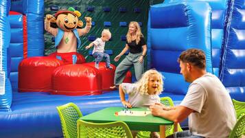 Ein Indoor-Spielbereich mit aufblasbaren Bauwerken und einem Tisch voller Spielzeug.