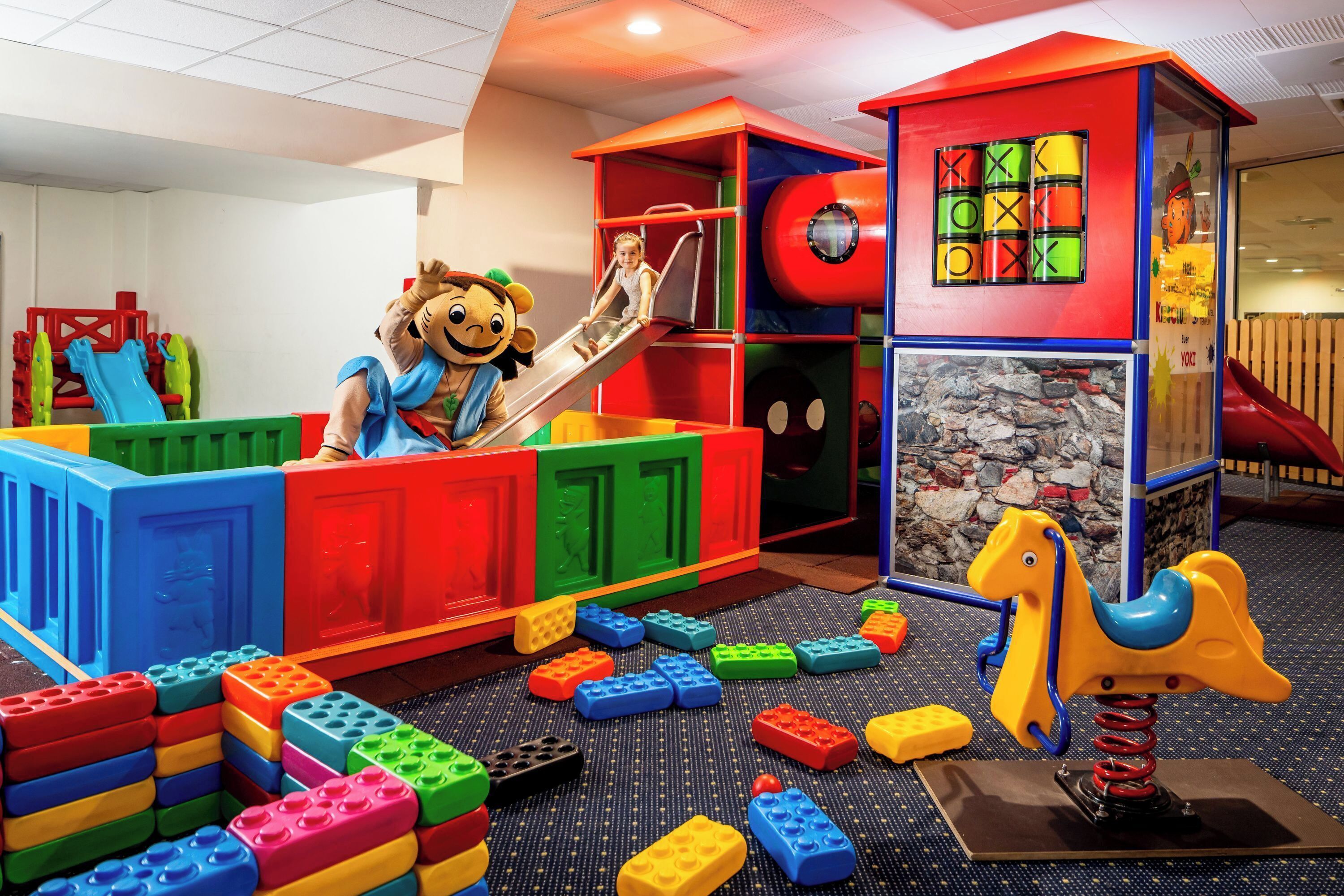 Un área de juegos infantiles con estructuras coloridas, que incluye un tobogán y una pared de escalar.
