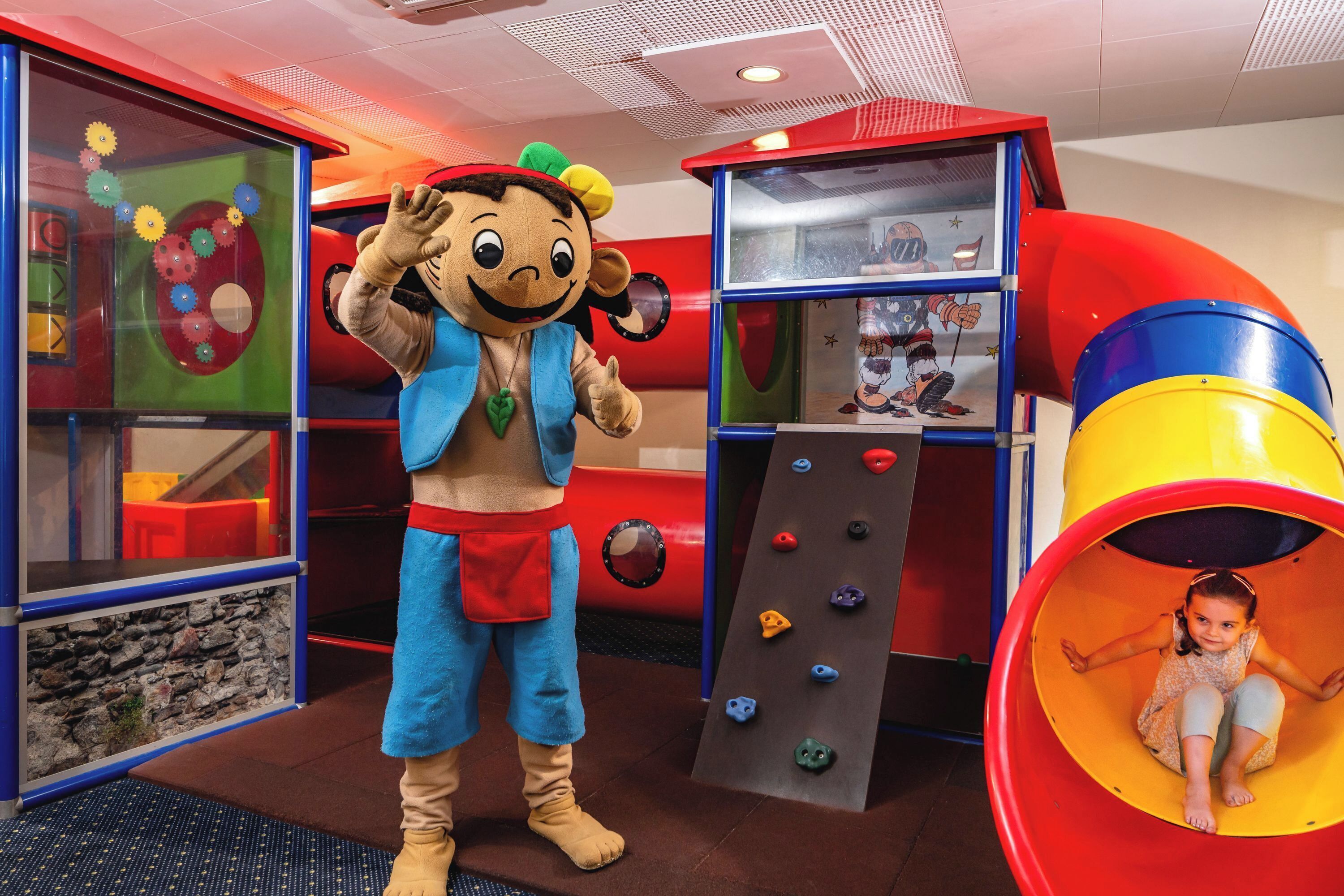 A play area with a slide, climbing wall, and a character mascot.