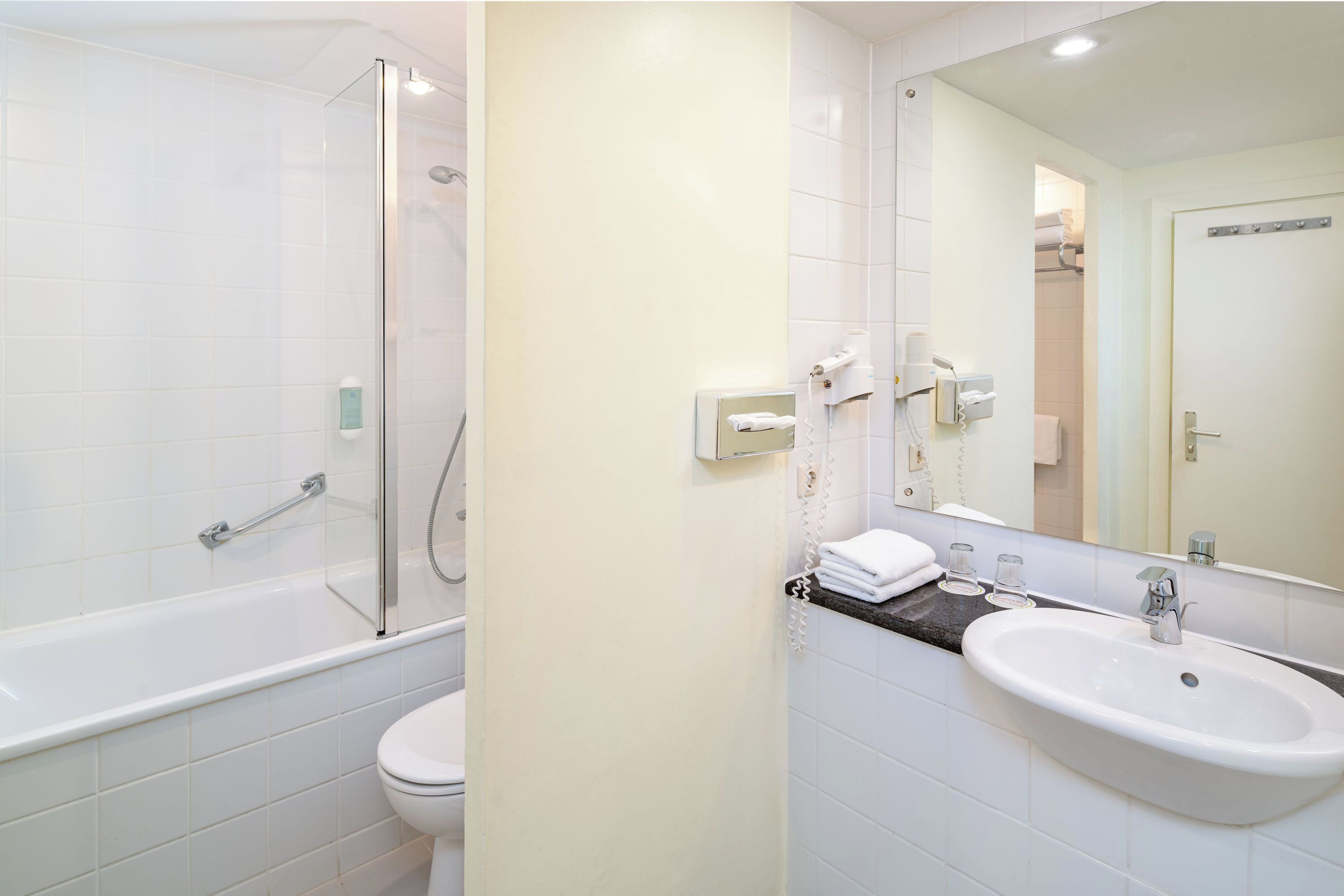 A modern bathroom with a glass-enclosed shower, a white toilet, and a sink with a mirror above it.