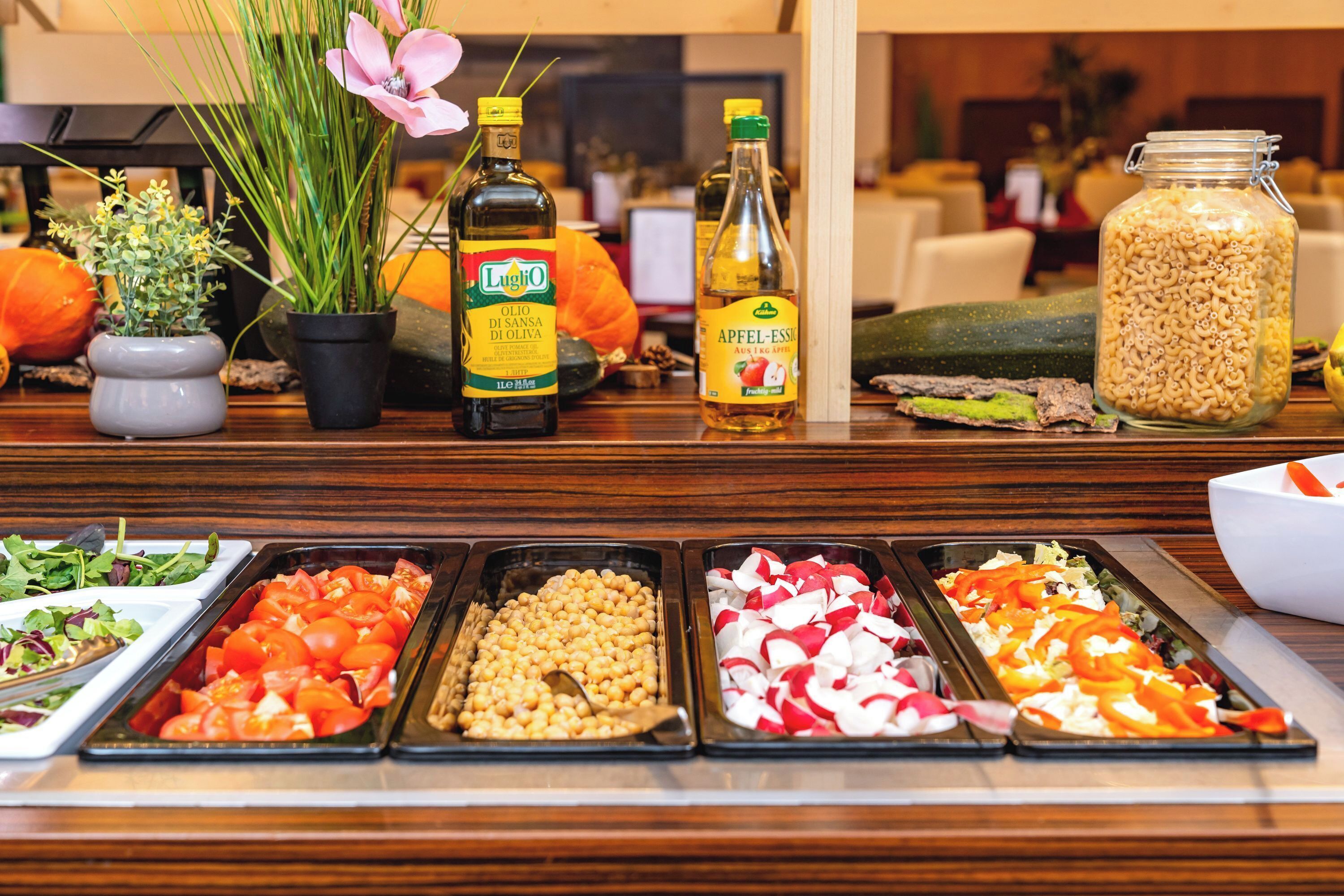Un bufé con diversas opciones de comida, entre ellas tomates, garbanzos, rábanos y pimientos.