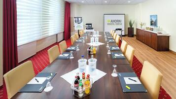 A conference room with a long table, chairs, water bottles, and a projector screen.