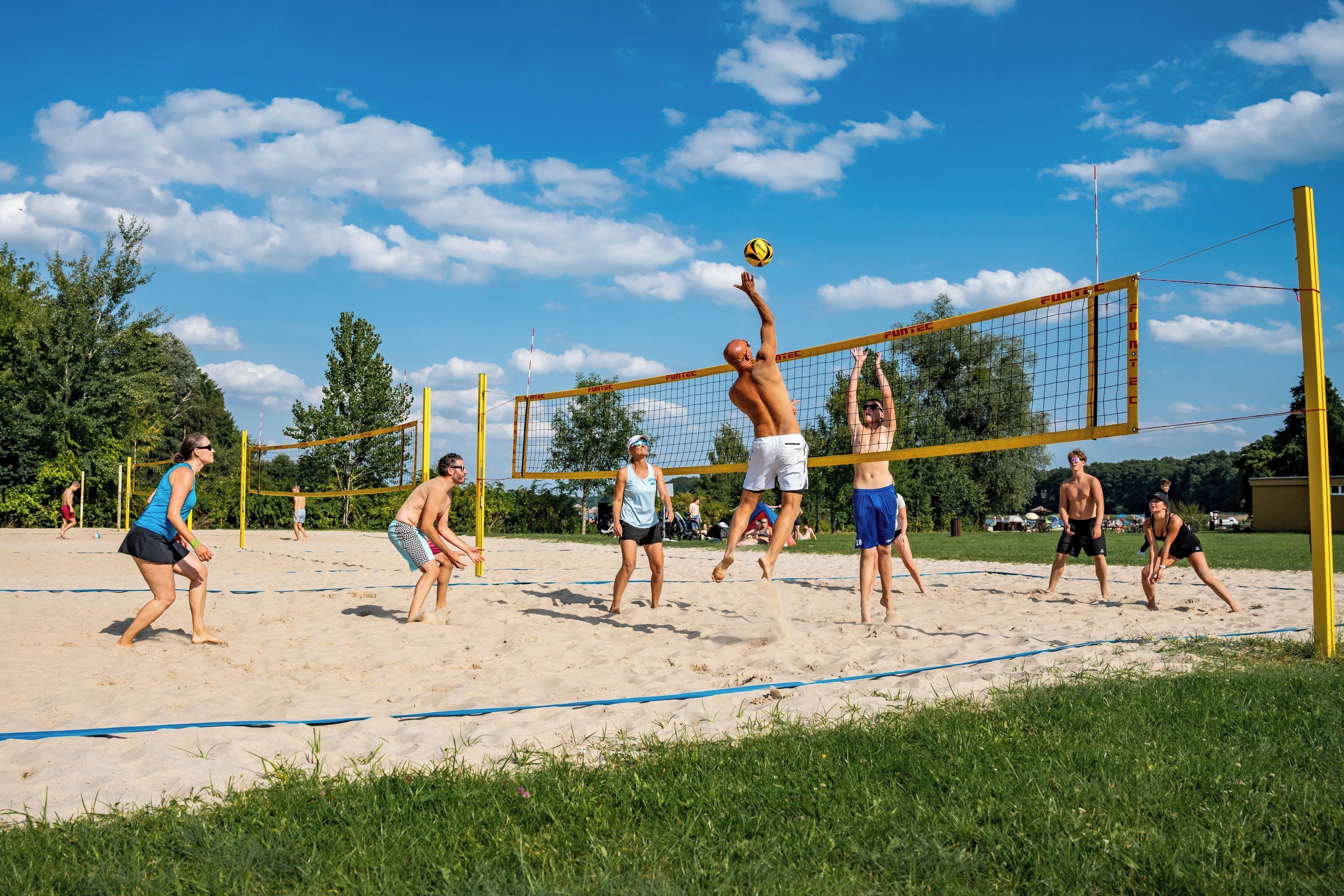 Partido de voleibol de playa en curso, con jugadores a ambos lados de la red.