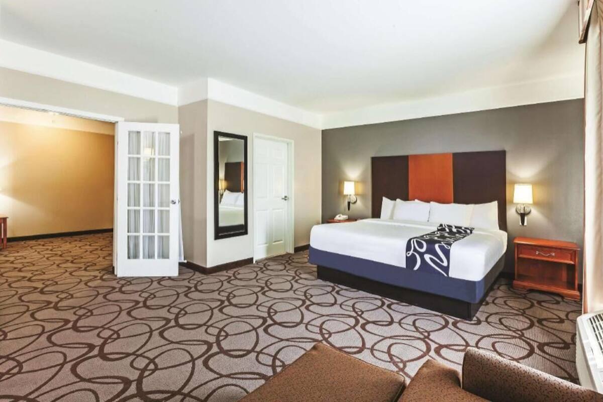 Een hotelkamer met een bed, nachtkastjes, een spiegel en een deur.