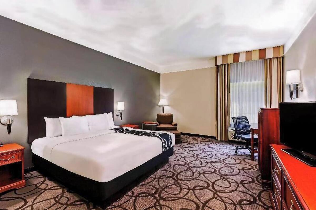 Una habitación de hotel con una cama grande, televisión, escritorio y una silla.