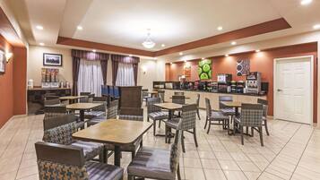 A restaurant with booths and tables, a counter with food items, and a door.