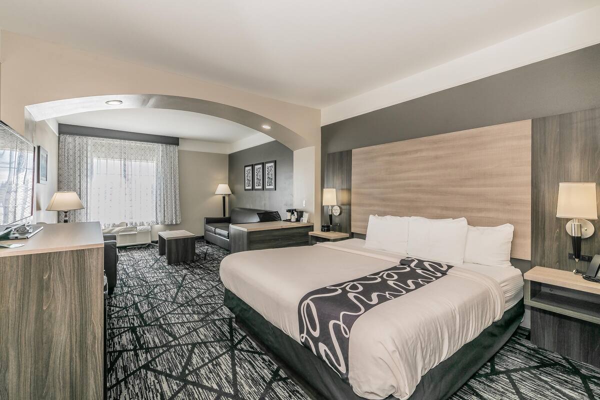 Een hotelkamer met een groot bed, een bureau, een stoel, een bank en een bureaulamp.