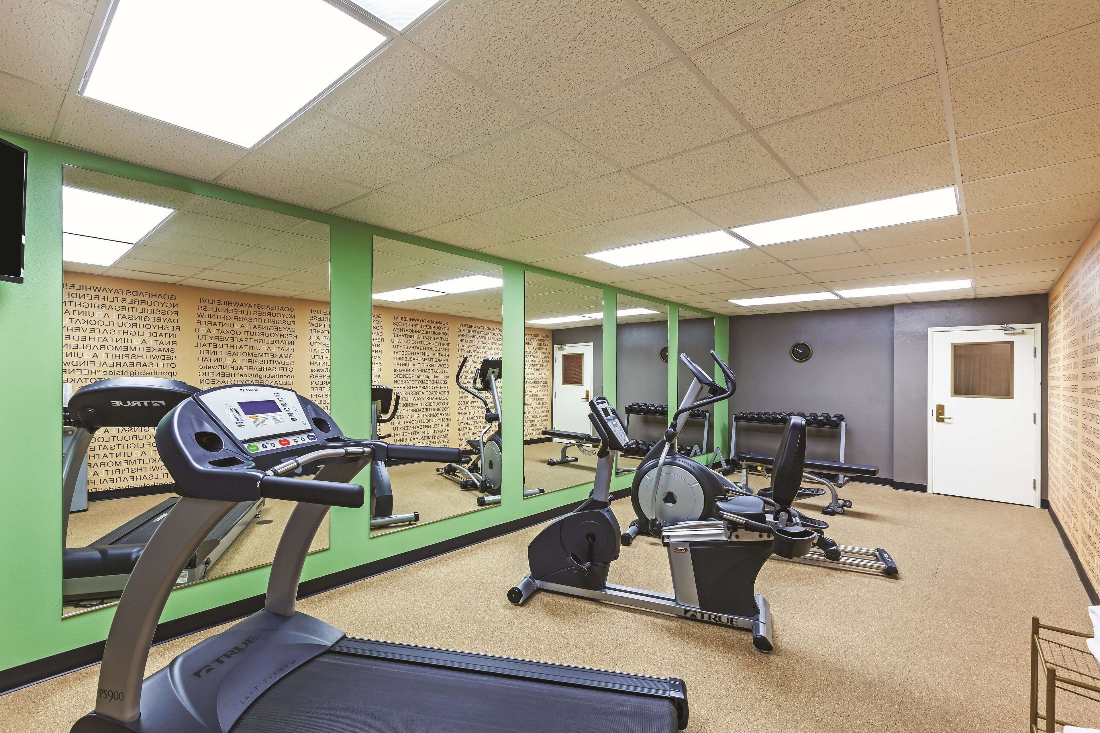Un gimnasio con cintas de correr, elípticas y pesas libres.