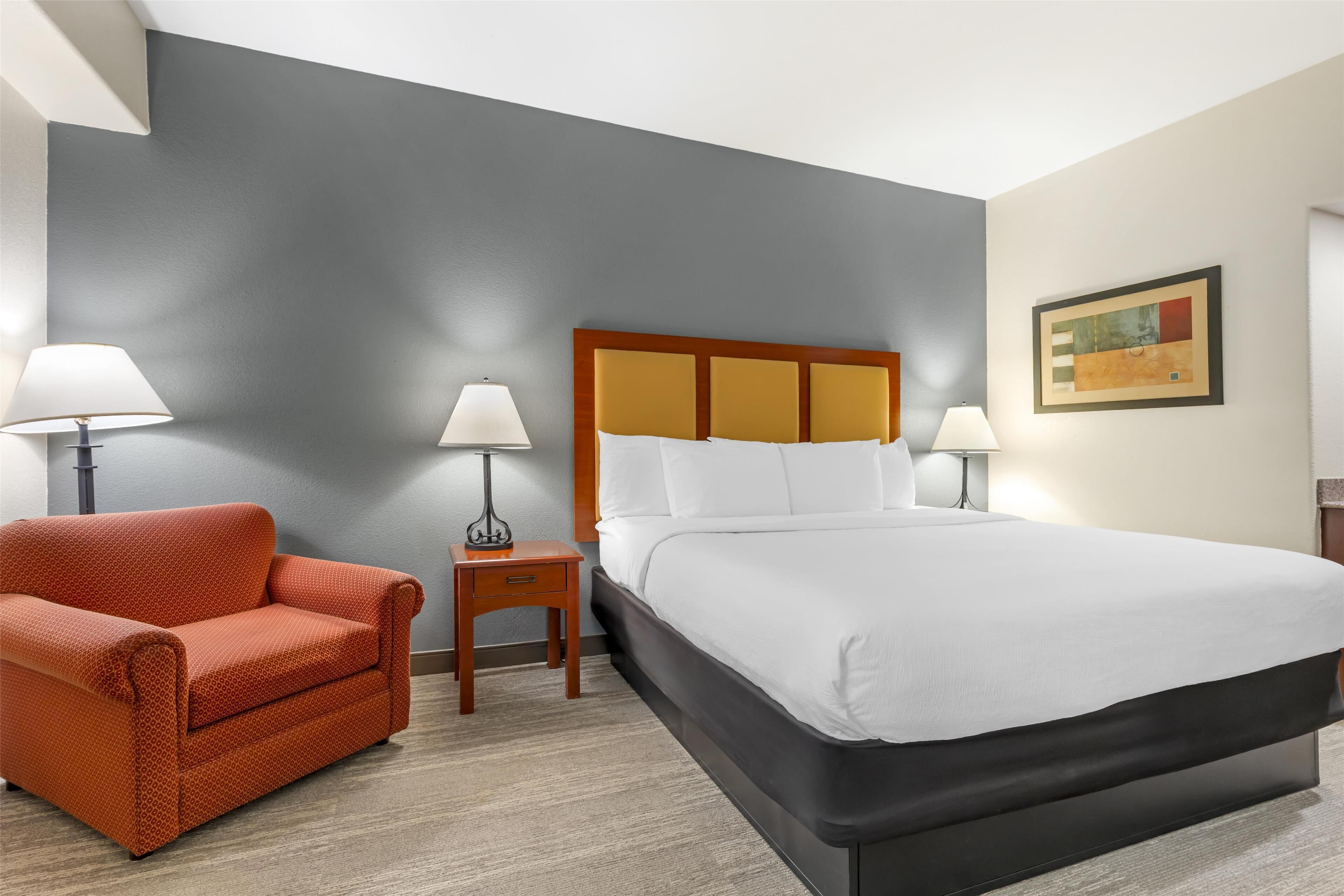 A hotel room with a bed, a sofa, two nightstands, and two lamps.