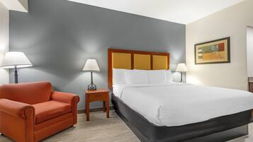 A hotel room with a bed, a sofa, two nightstands, and two lamps.