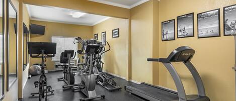 Un gimnasio con equipo de ejercicio, una cinta de correr y carteles motivacionales en la pared.