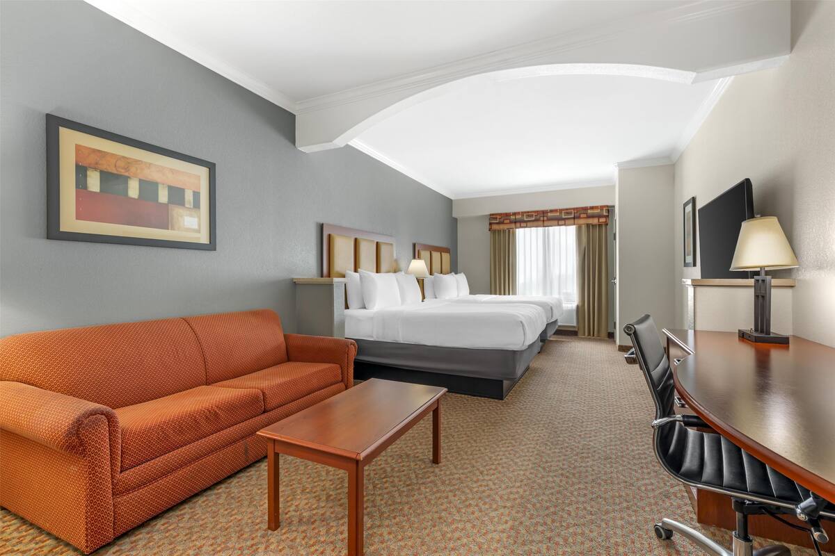 A hotel room with a bed, a sofa, a desk, and a TV.