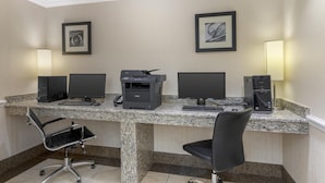 A hotel office with a granite desk, two monitors, a printer, and two chairs.