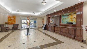 A hotel lobby with a reception desk, seating area, and artwork on the walls.